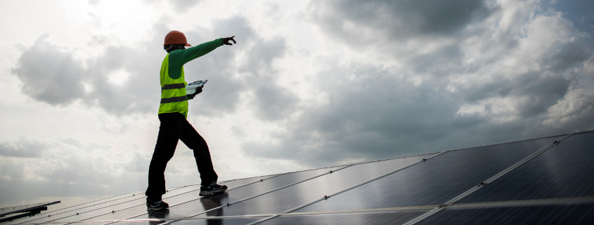 Man standing on solar panels pointing at cloudy sky